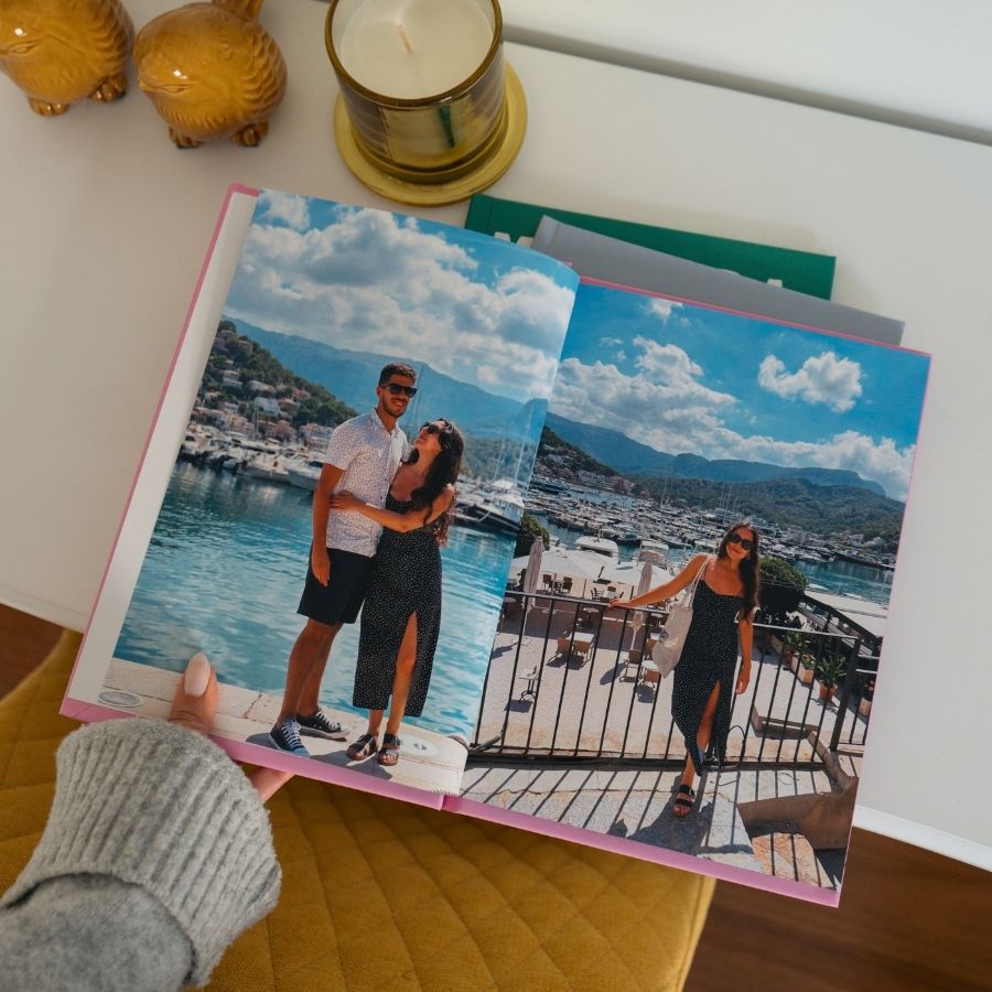 Álbum aberto com fotografias de férias junto ao mar, seguro por uma mão.